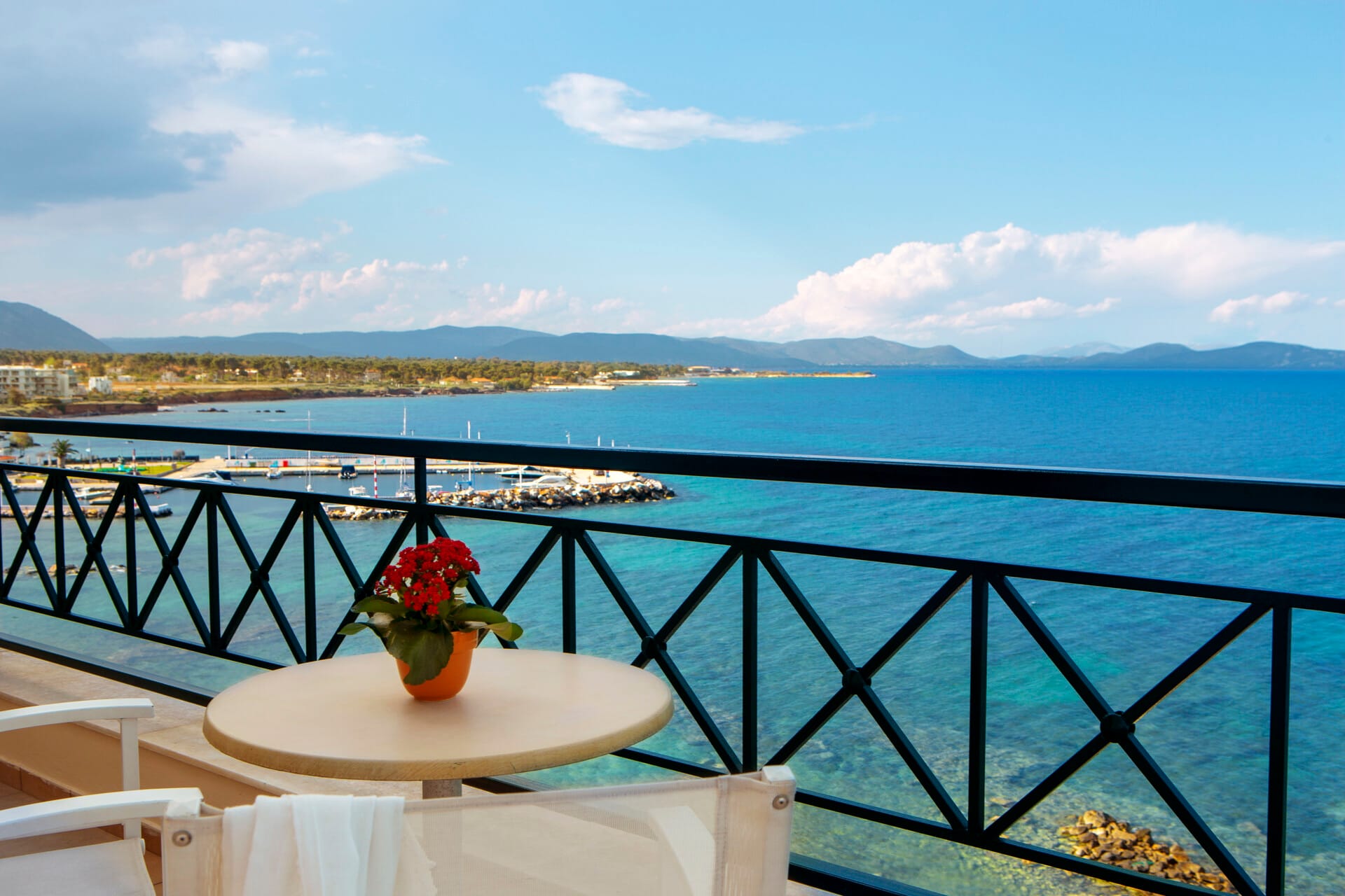 a table with a flower on it by a railing overlooking a body of water