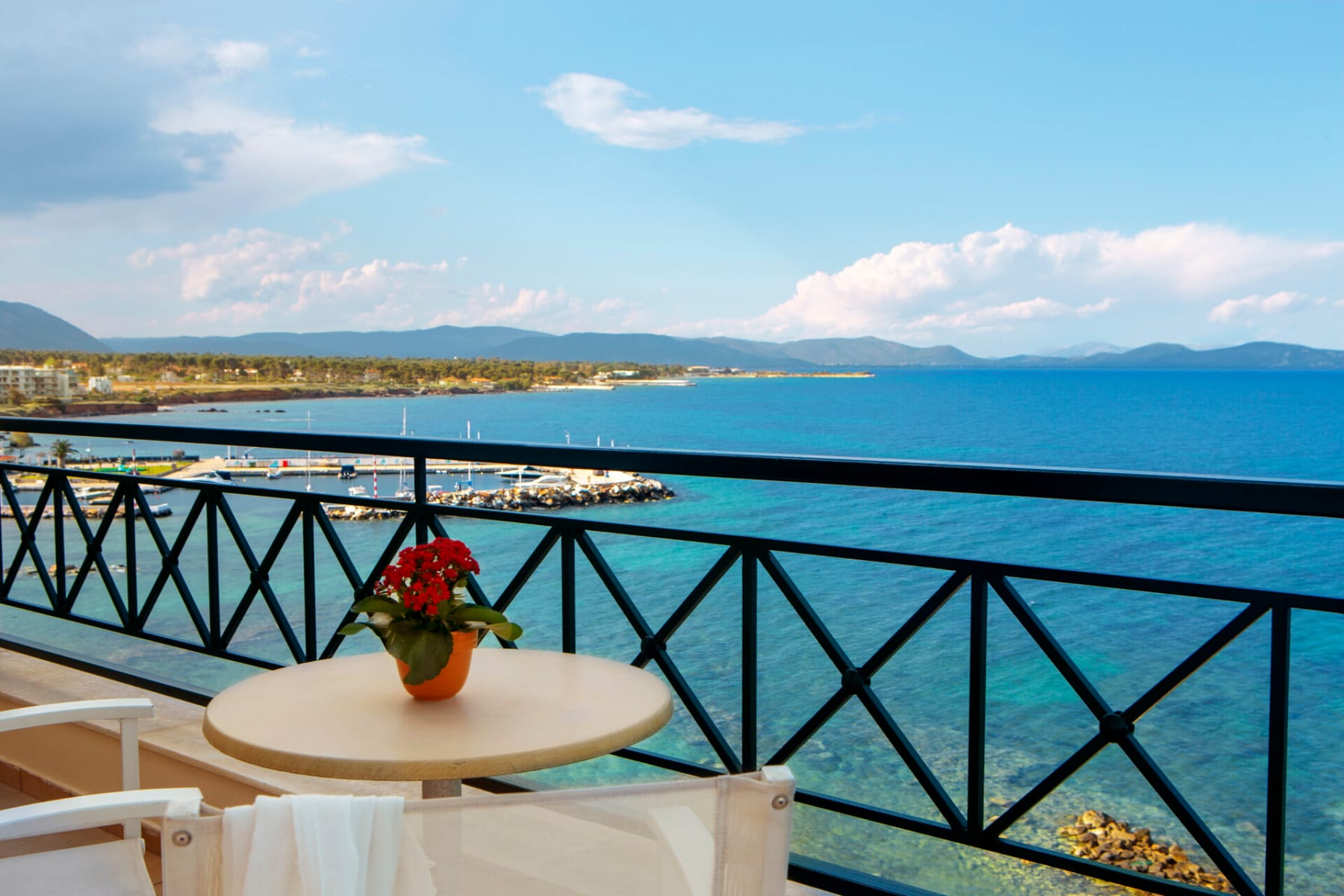 a table with a flower on it by a railing overlooking a body of water
