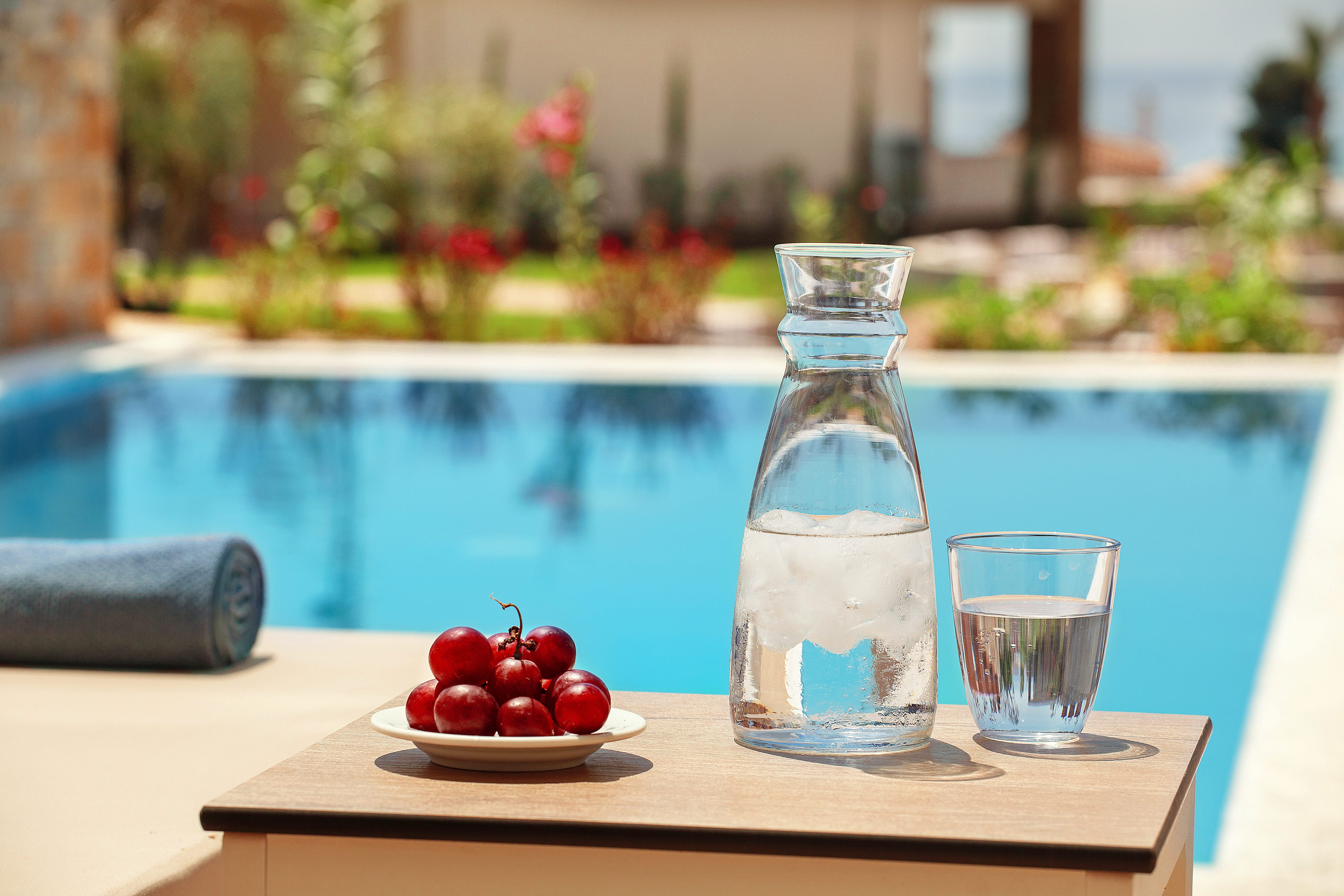 a glass of water and a plate of cherries on a table