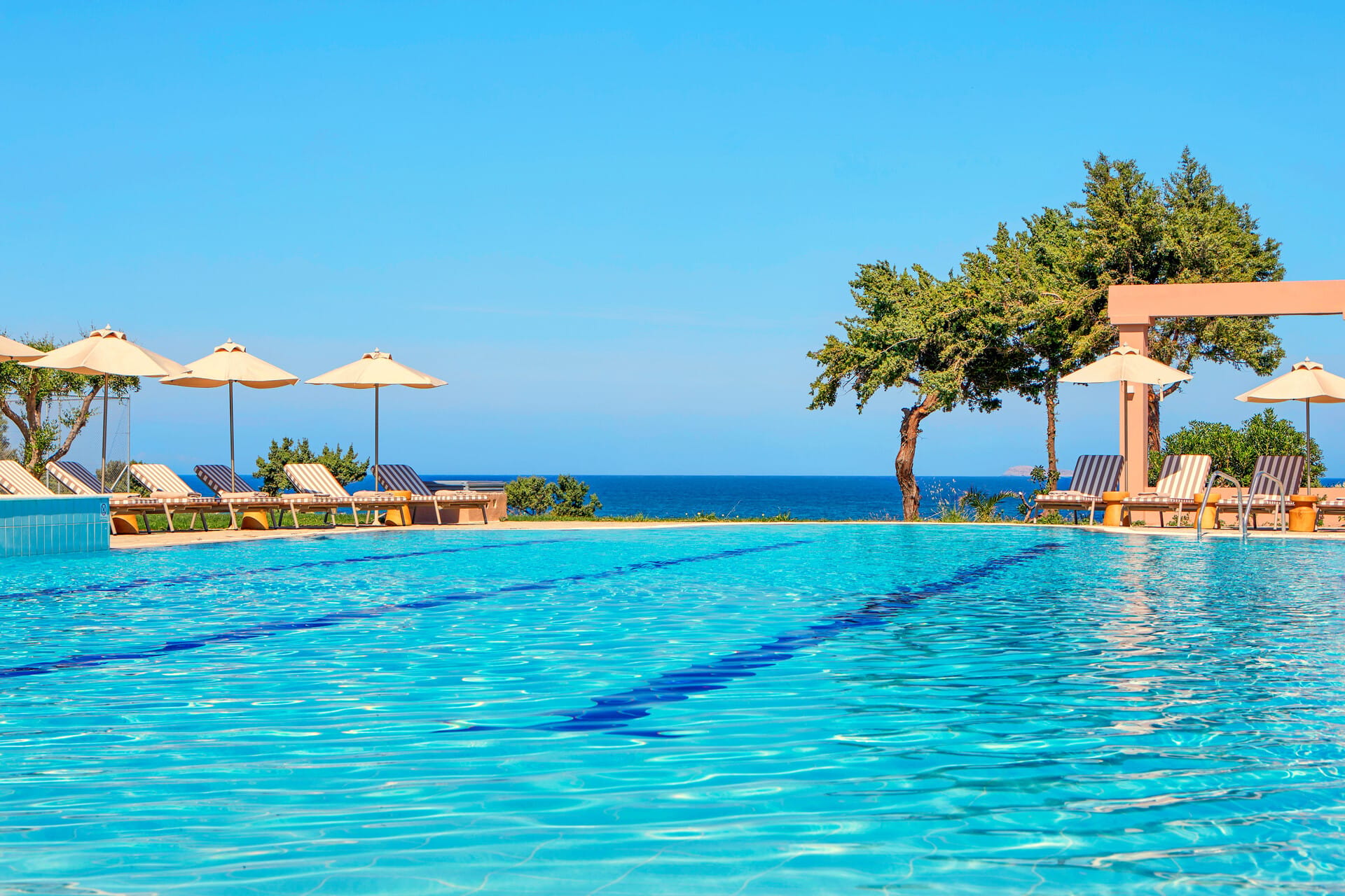 a pool with chairs and umbrellas by a beach