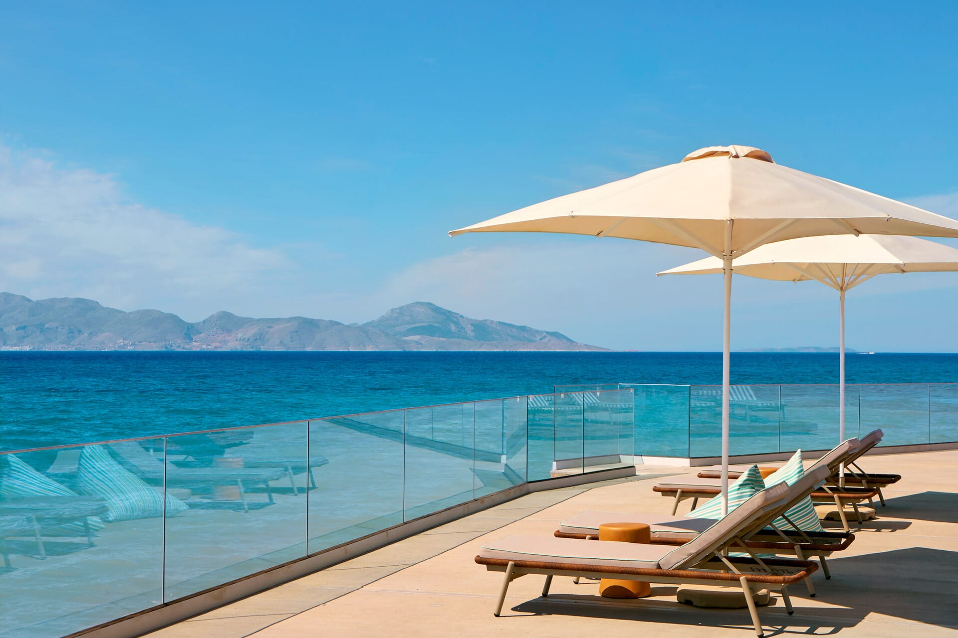 chairs and umbrellas on a deck by a body of water