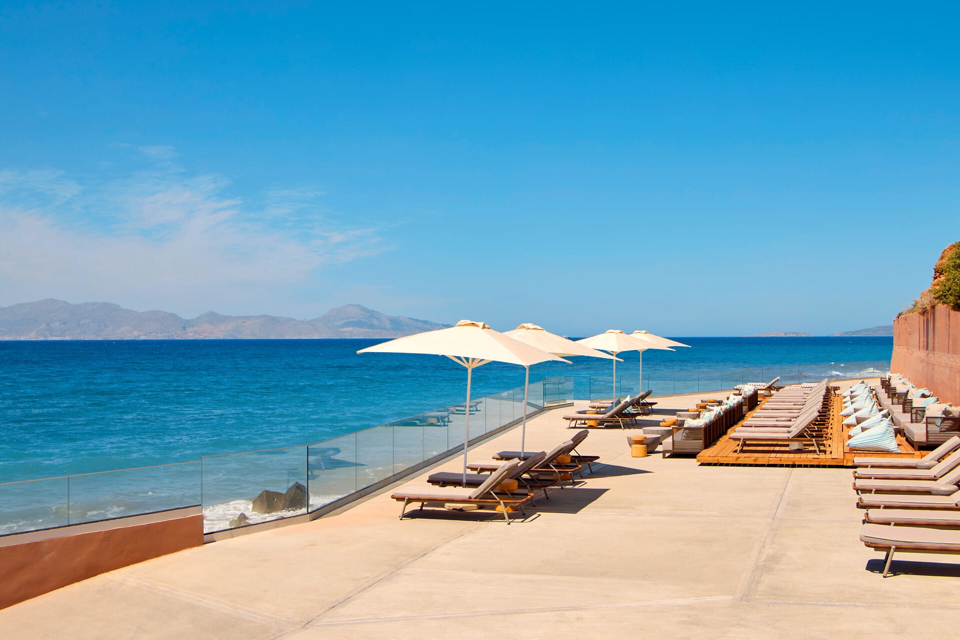 a deck with chairs and umbrellas on it by the water