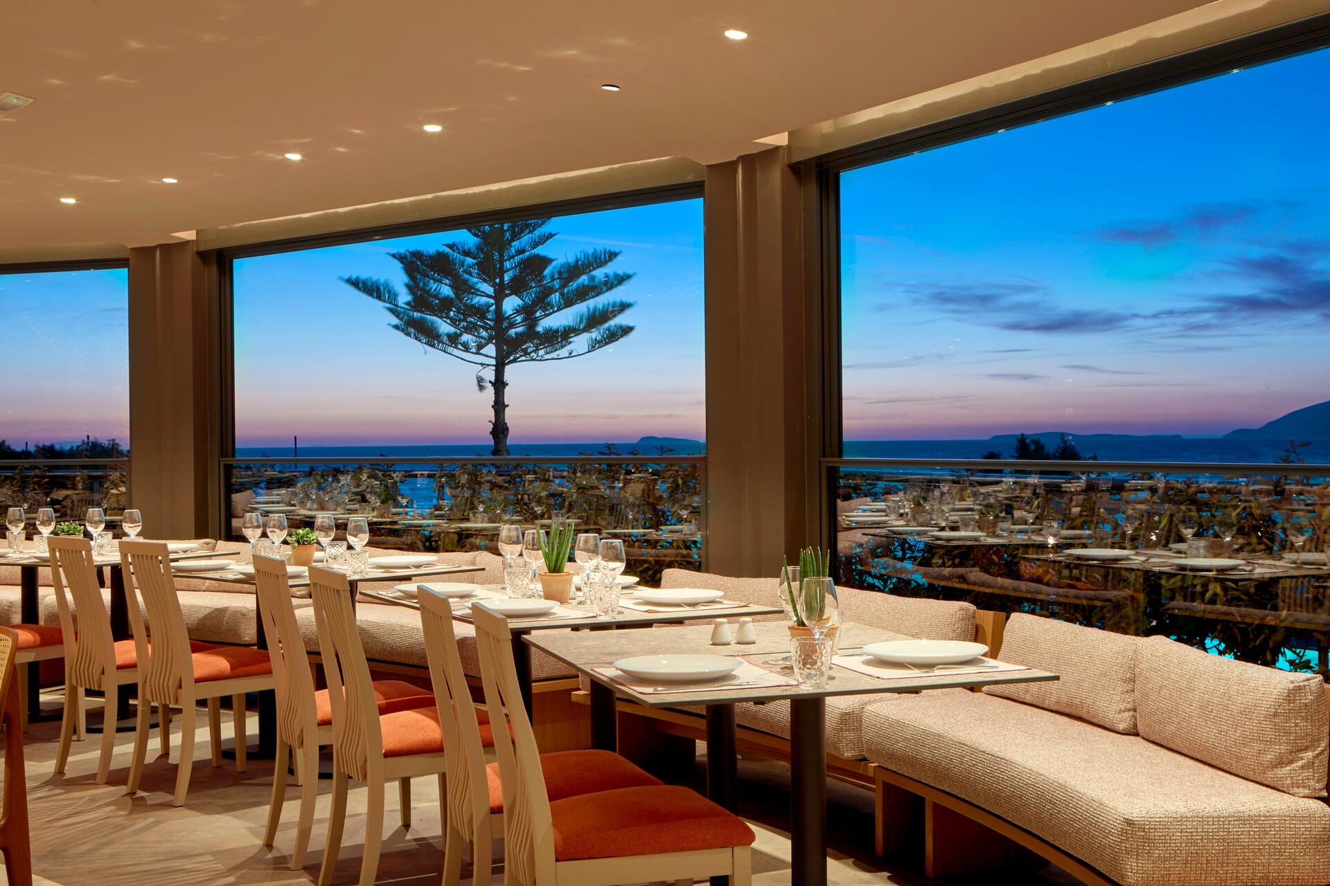 a room with a large window and a large table with chairs and a large body of water in