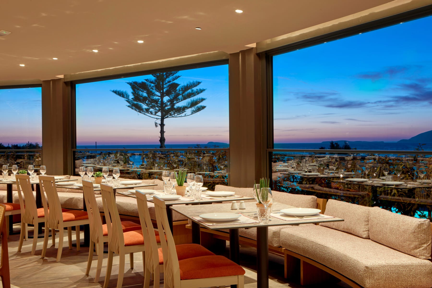 a room with a large window and a large table with chairs and a large body of water in