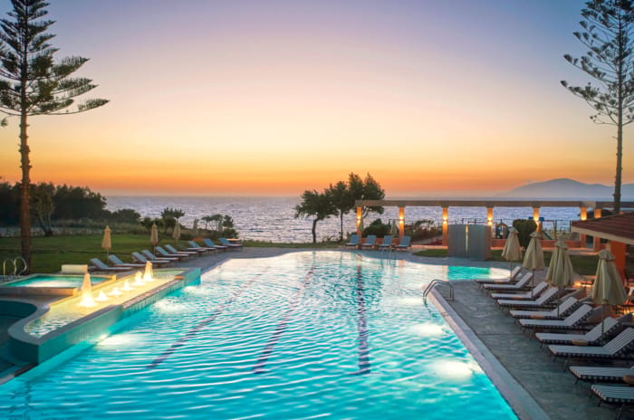 a pool with chairs around it by a beach and trees