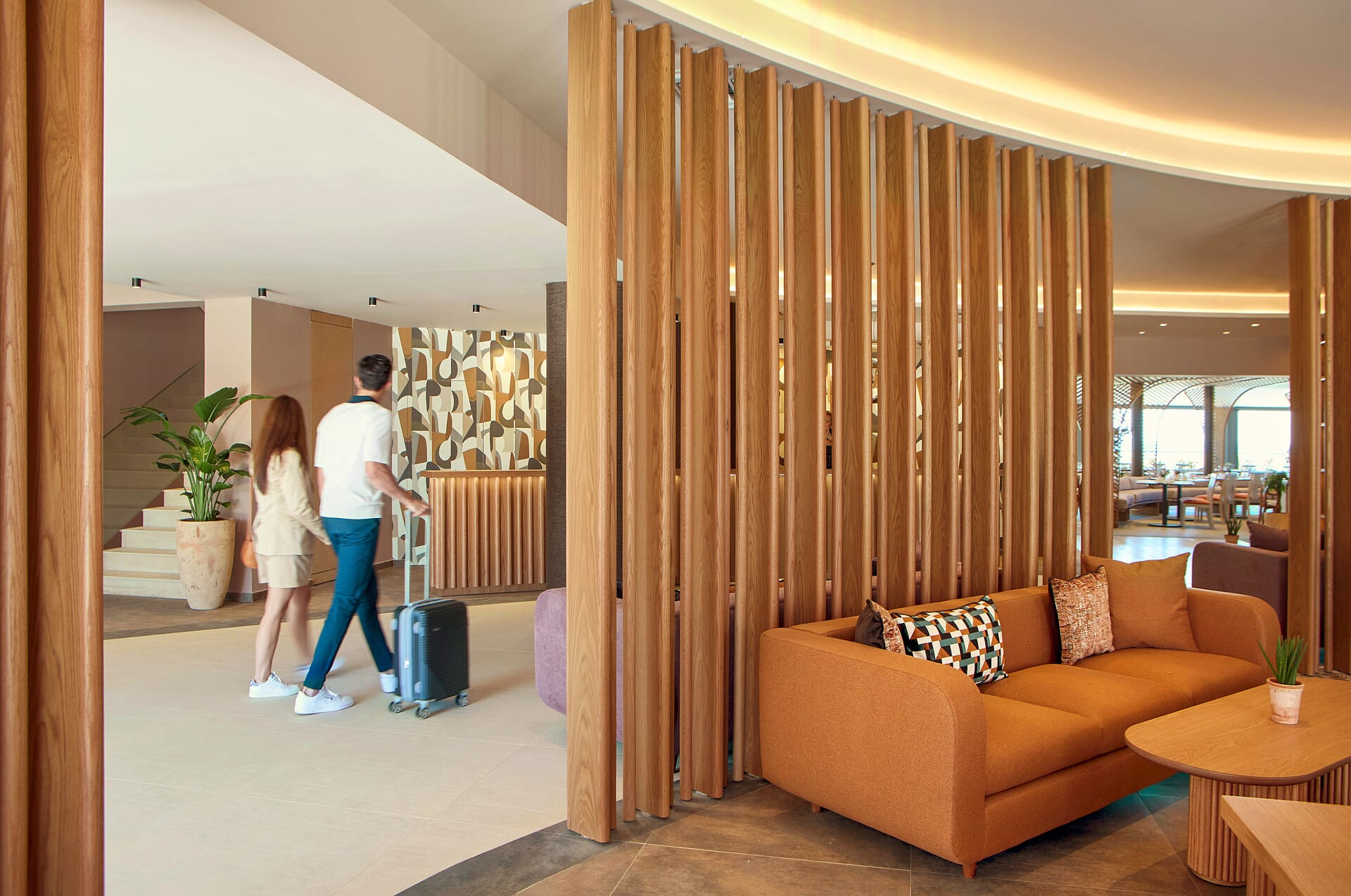a man and a woman walking in a room with a couch and a table