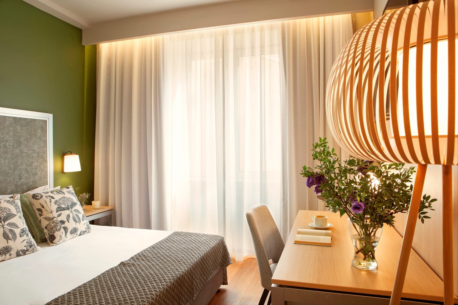 a bedroom with a bed and a table with a vase of flowers