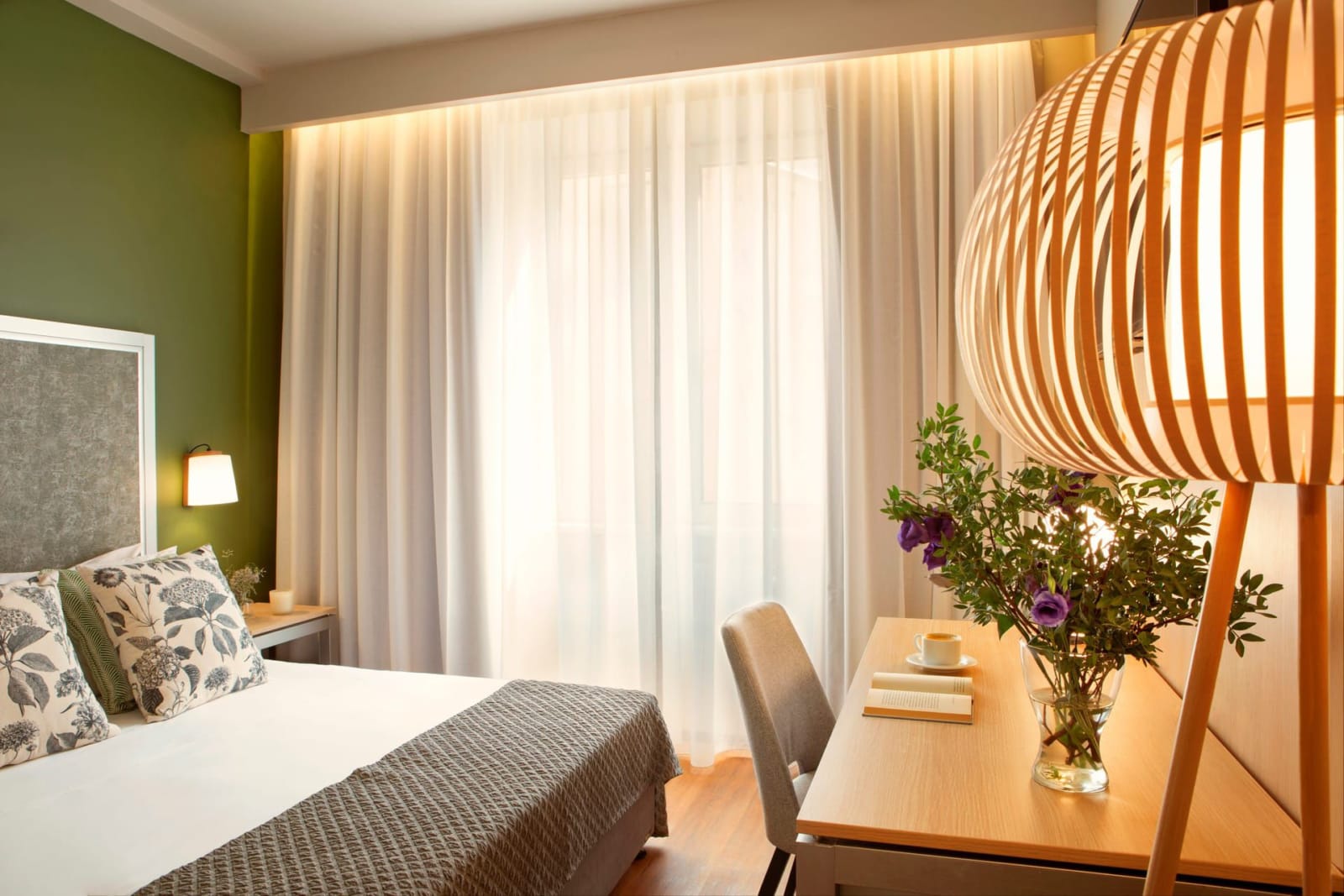a bedroom with a bed and a table with a vase of flowers