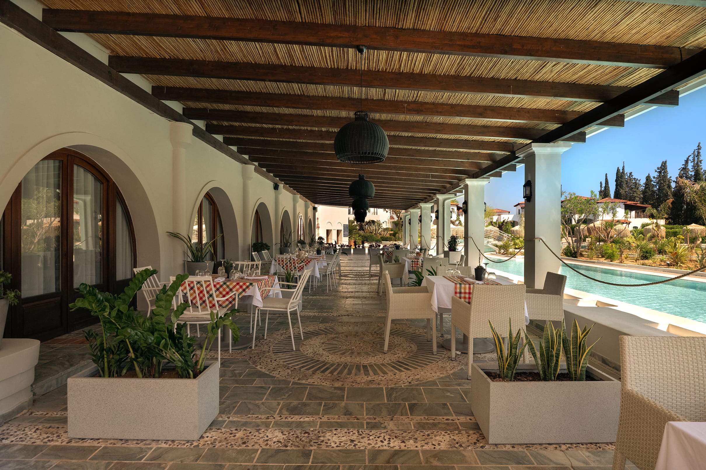 a patio with tables and chairs and a pool