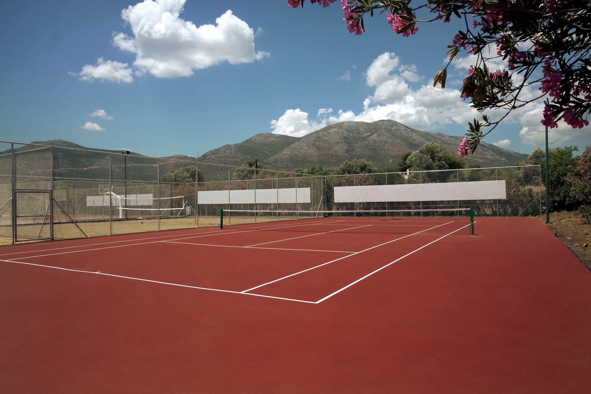 a tennis court with a fence and trees in the background