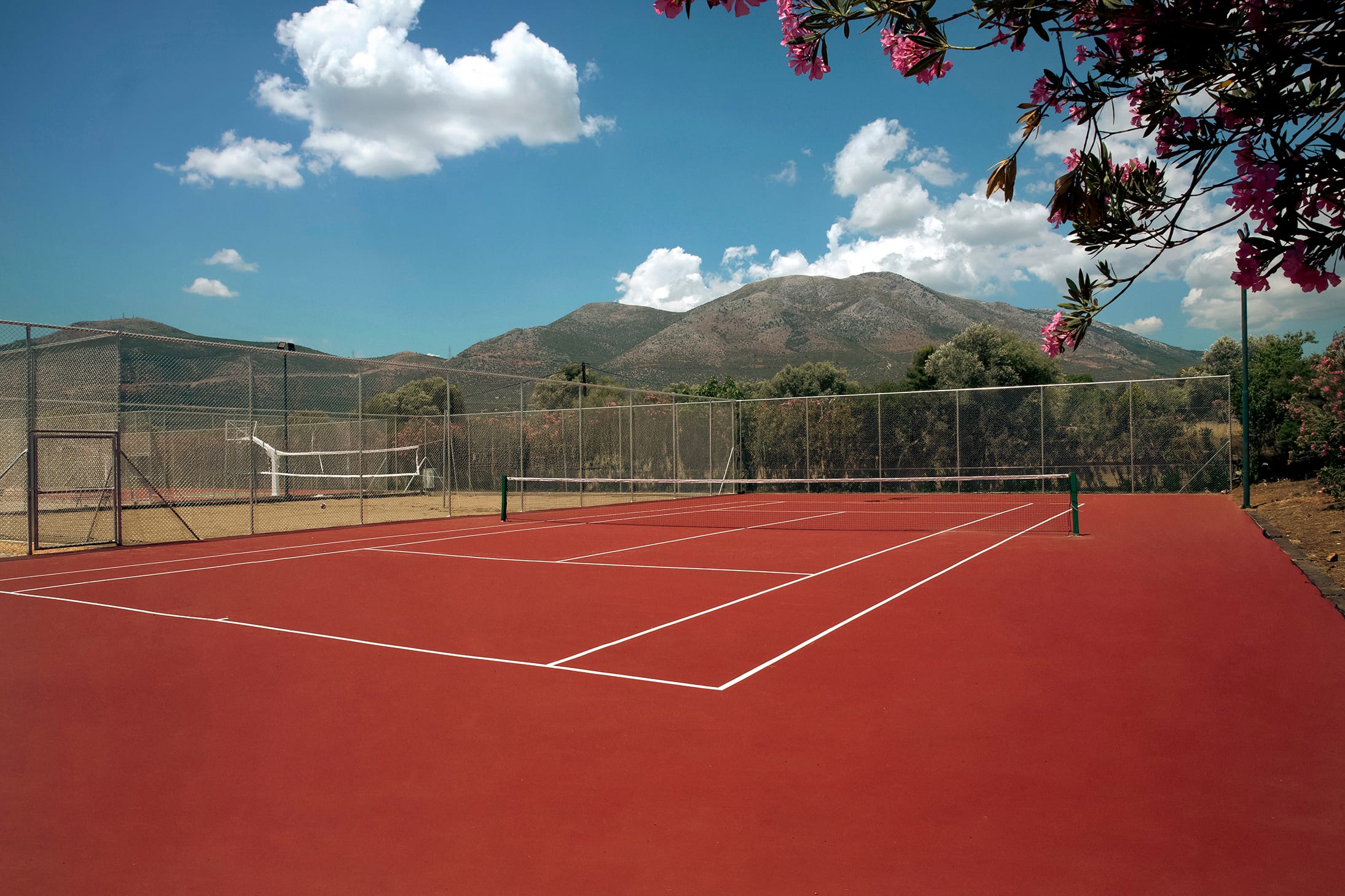 a tennis court with a fence and trees in the background