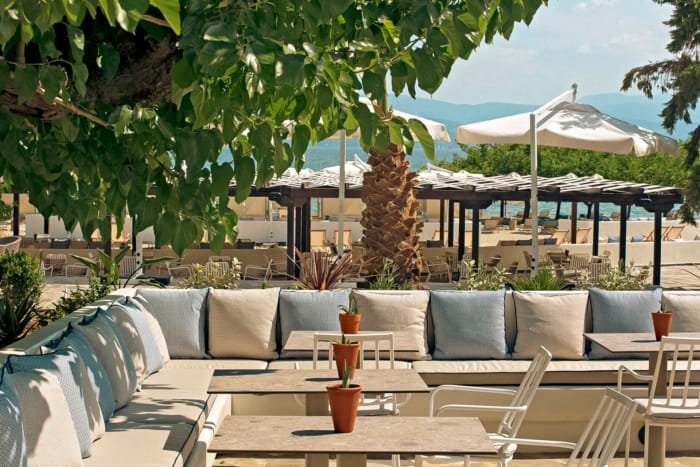 a patio with white chairs and umbrellas