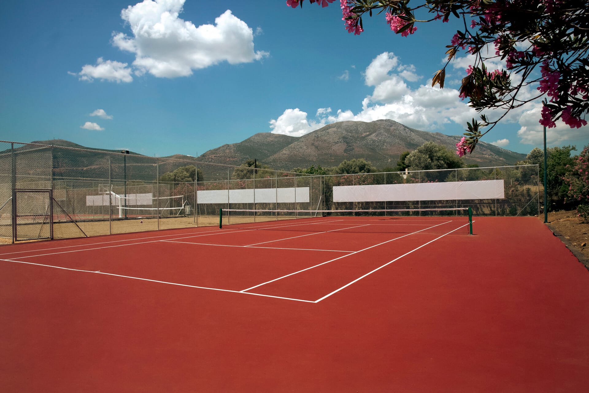 a tennis court with a fence and trees in the background