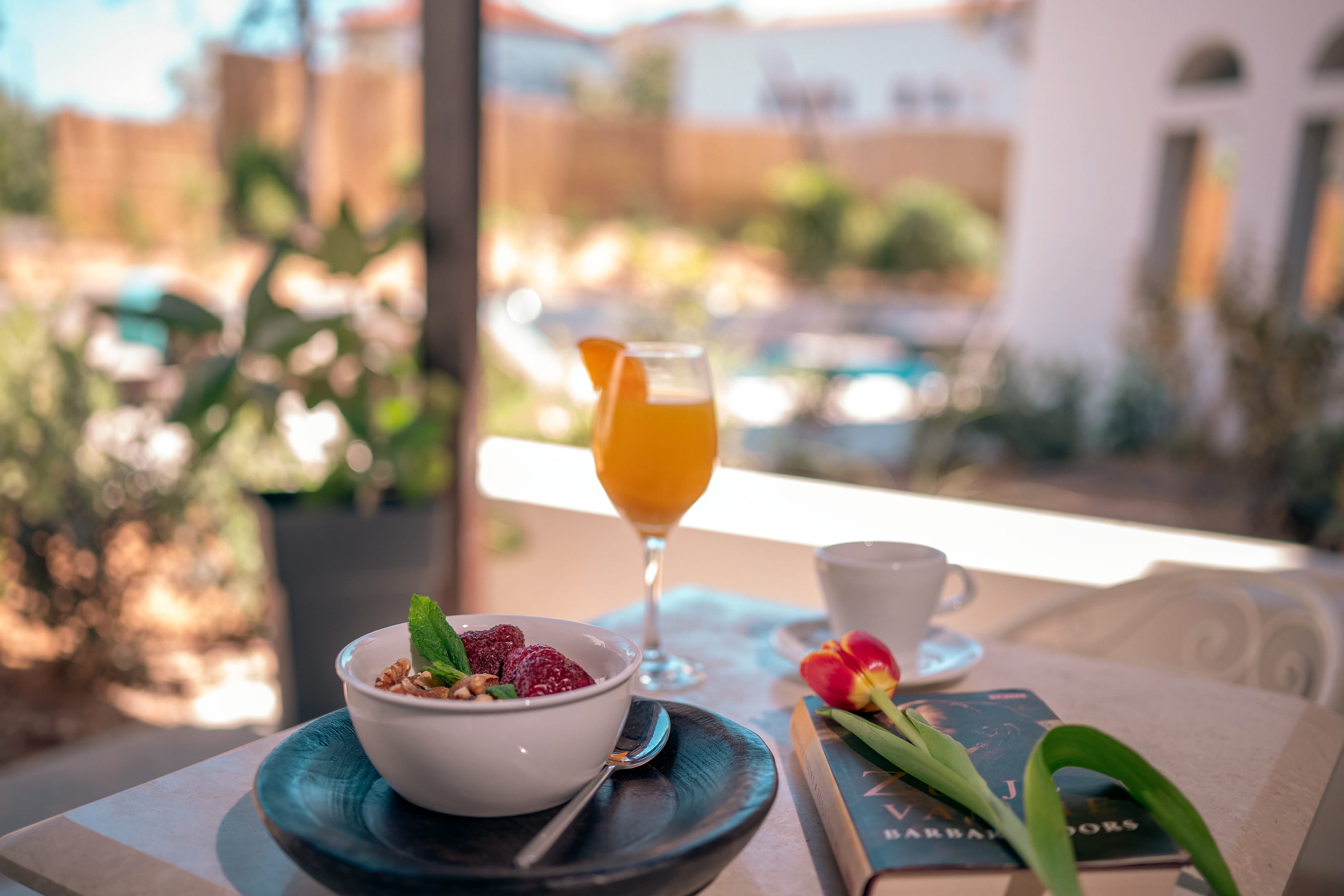 a glass of orange juice and a bowl of fruit on a table