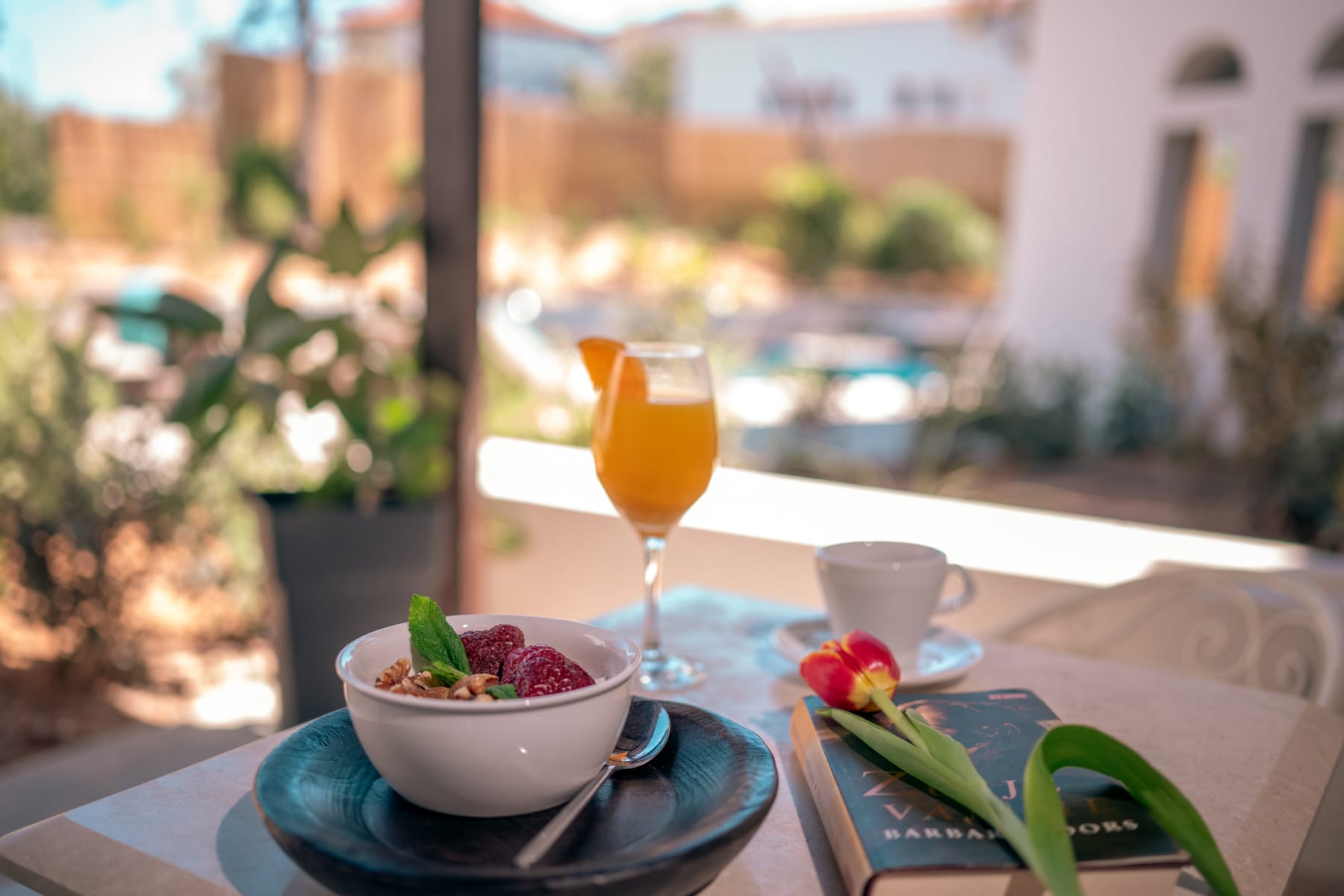 a glass of orange juice and a bowl of fruit on a table