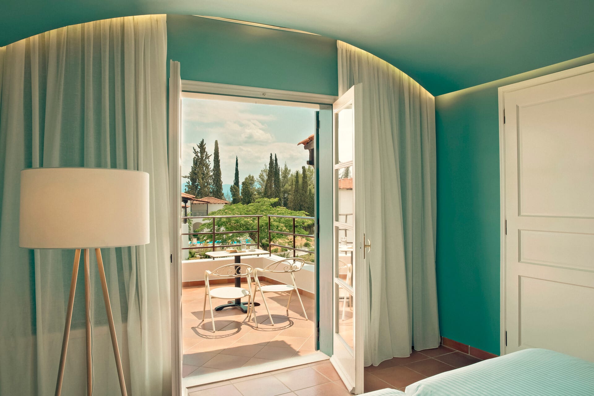 a room with a window and a table with a lamp and a view of trees