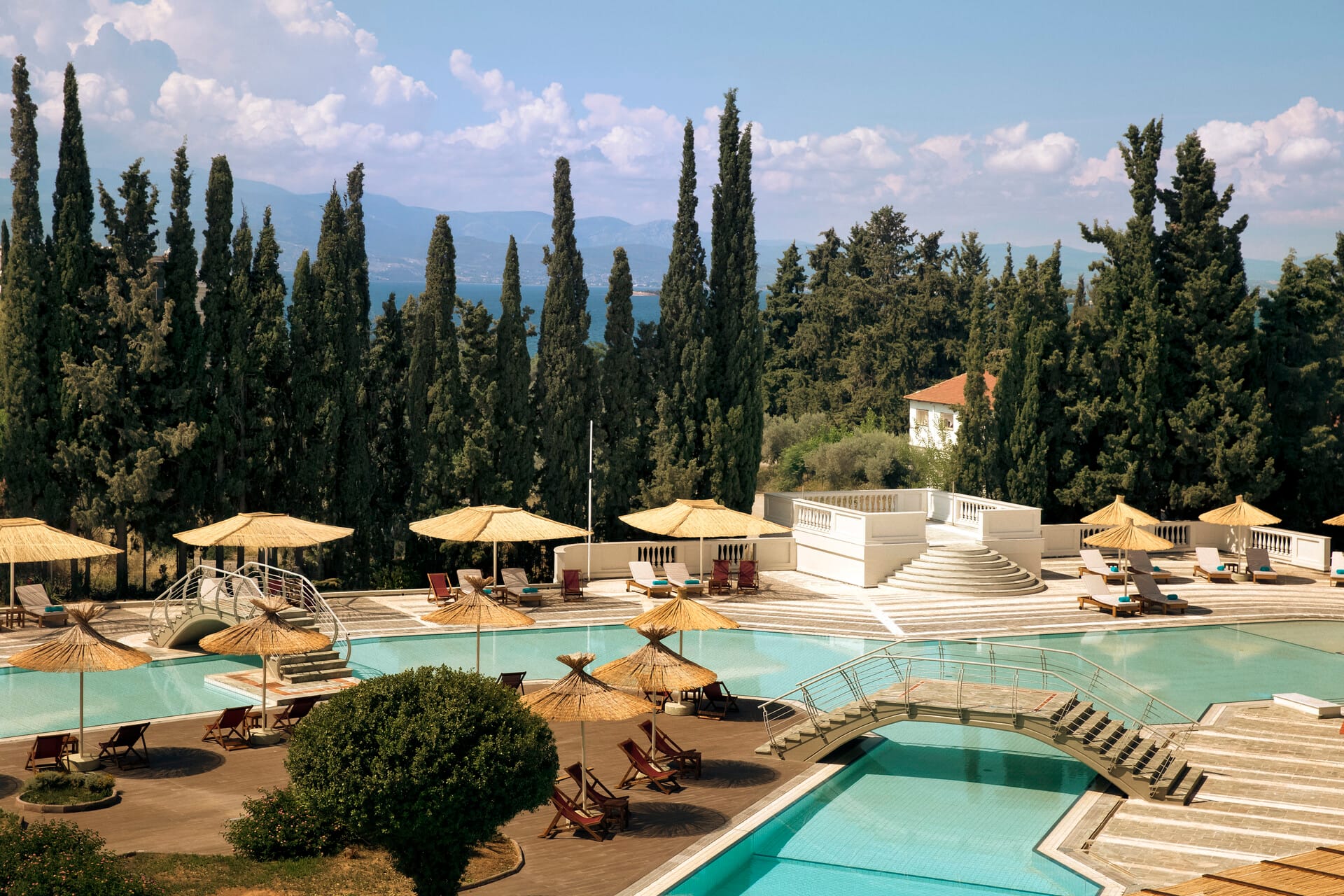 a pool with umbrellas and chairs next to a beach