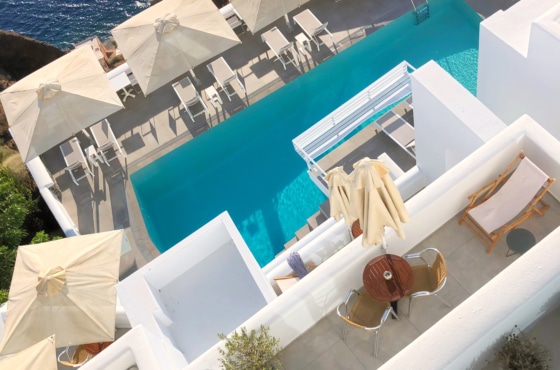 a pool with a lounge chair and umbrellas by a beach