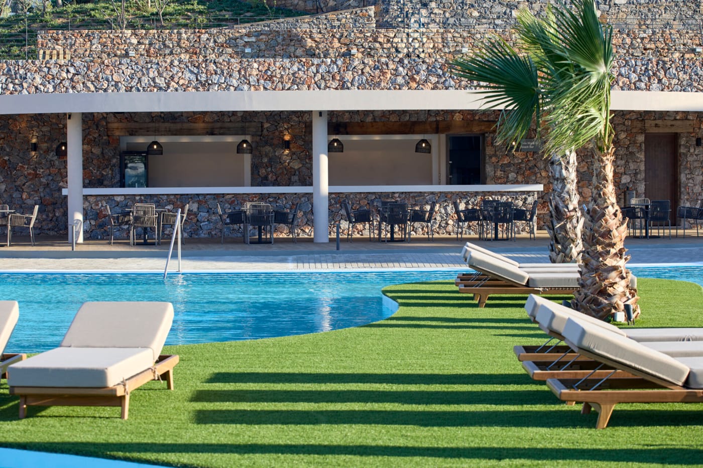 a pool with lounge chairs and a tree in front of it