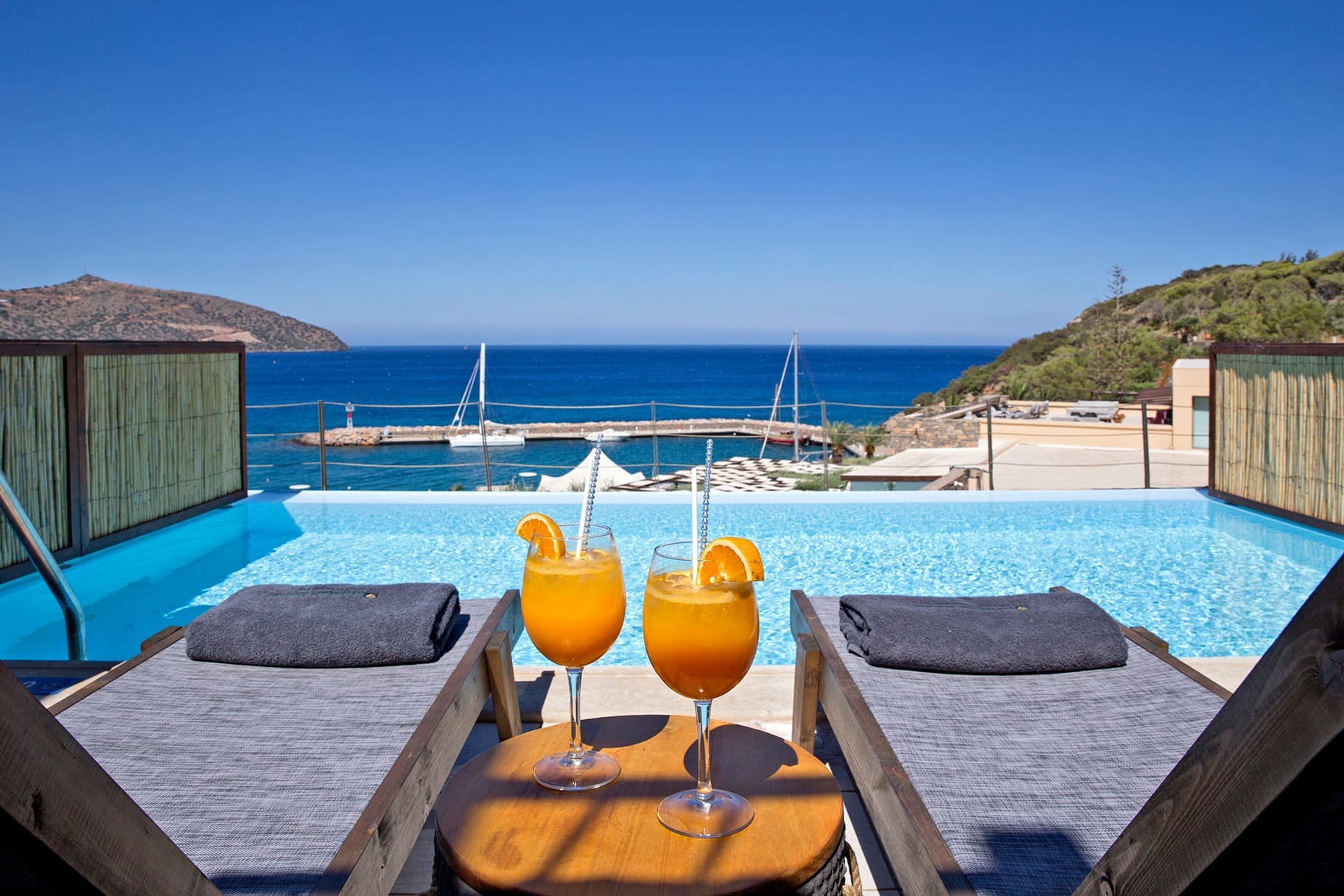 a couple of glasses of wine on a table by a pool