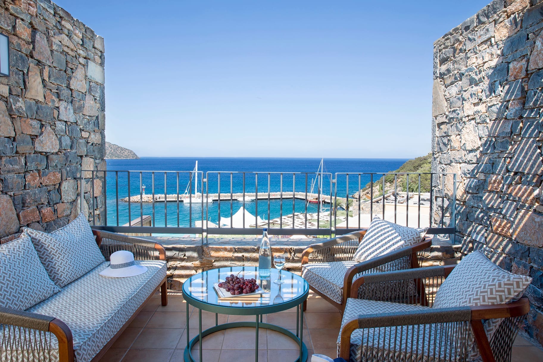 a patio with chairs and a table with a view of the ocean
