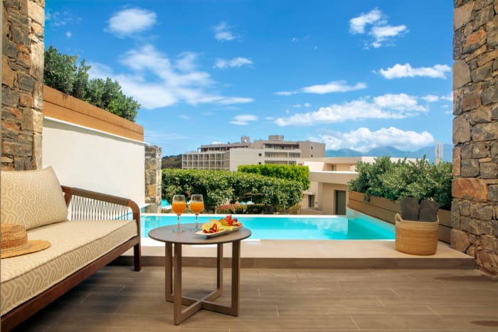 a table and chairs on a patio with a pool in the background